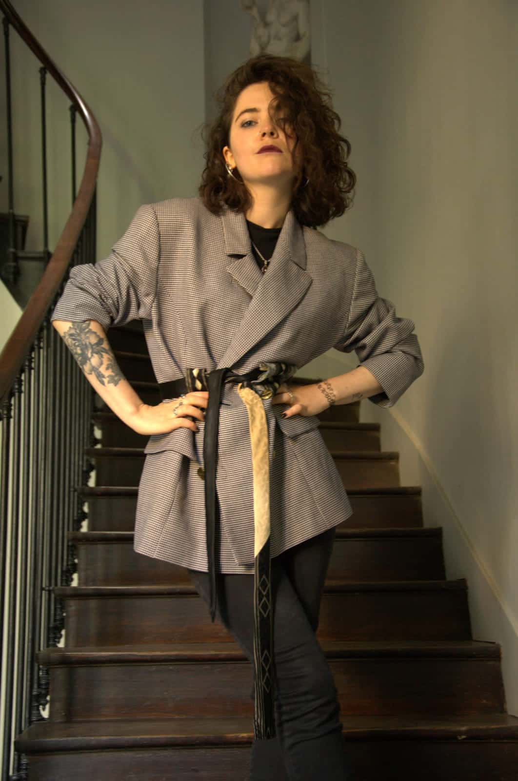 Blazer clair à petits carreaux, porté ceinturé, dans un escalier
