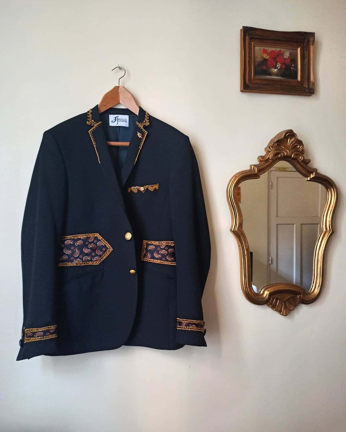 Blazer bleu nuit sur un cintre, revers brodés de doré, poches et poignets à empiècements à motif cachemire