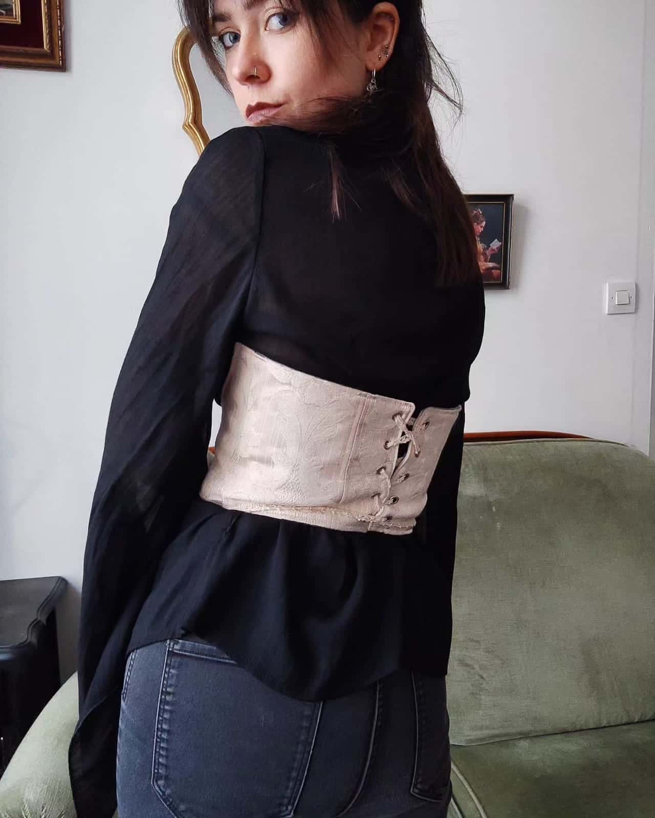 Bustier beige à motif ton sur ton, lacé dans le dos, porté sur un chemisier noir transparent