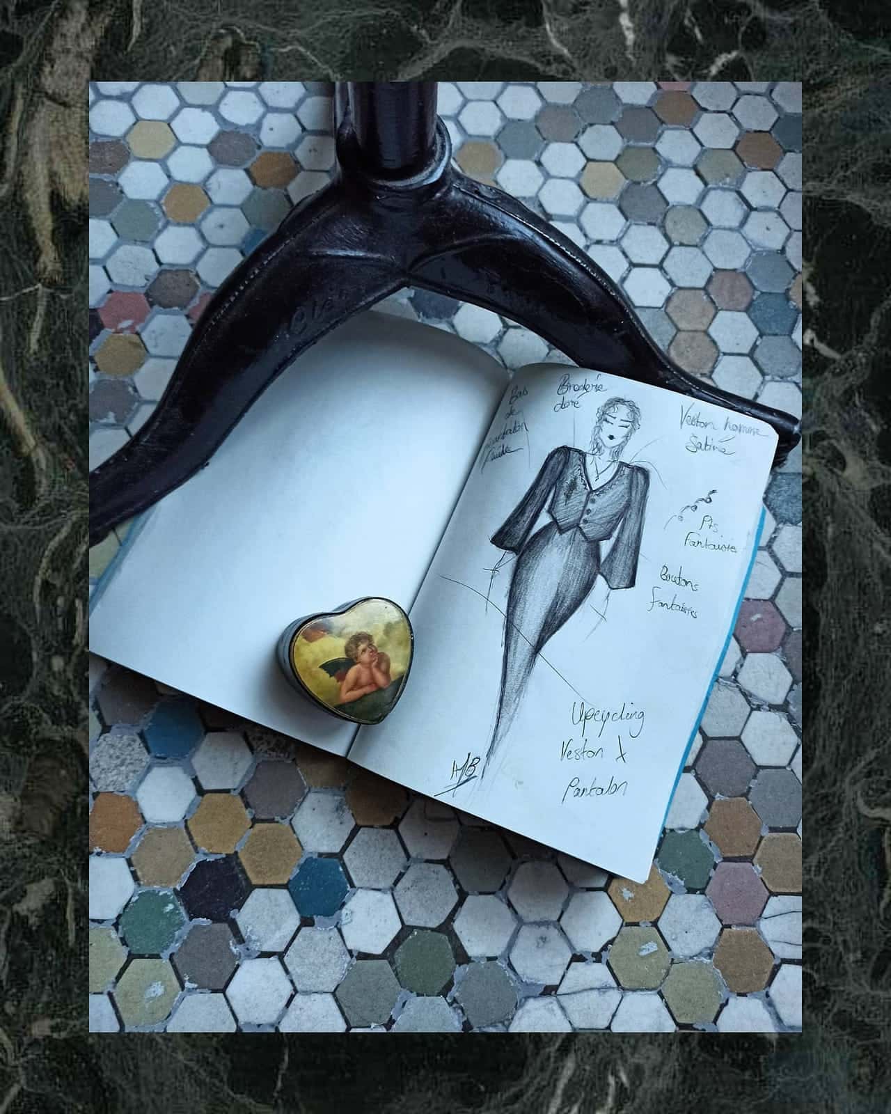 Carnet de croquis posé à côté d’une broche dorée