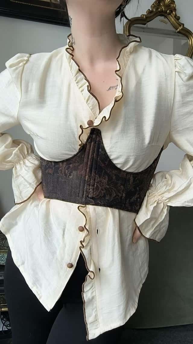 Corset à motif floral sombre porté sur un chemisier crème, vu de face