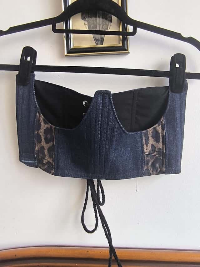 Corset en jean à bonnets noirs et panneau léopard, sur un cintre