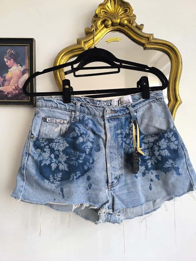 Short en jean sur un cintre, motifs végétaux blancs imprimés au cyanotype