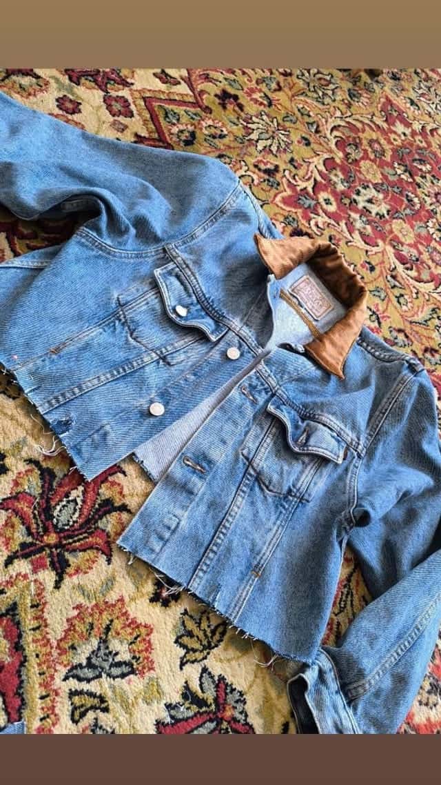 Veste en jean clair posée à plat sur un tapis, col doublé de suédine brune et ourlet coupé à vif