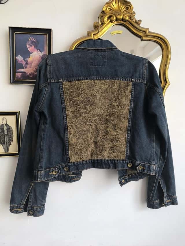 Dos de la veste en jean sombre, panneau de brocart doré cousu au milieu